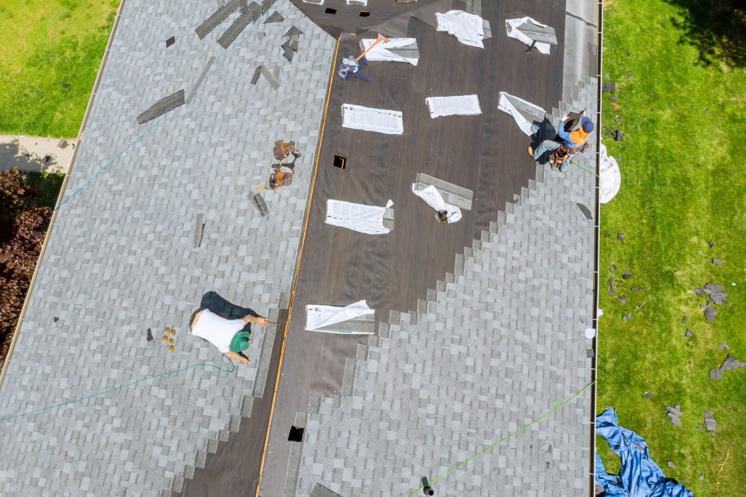 Roofer working on replacement asphalt shingle roof construction